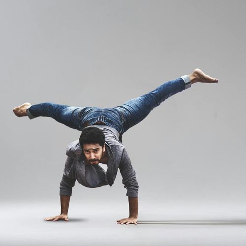 A person performing a strength-based yoga pose against a nectarine-colored background.